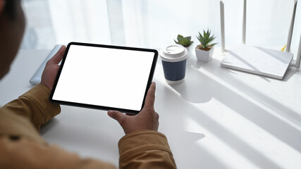 Close up back view of man young man using digital tablet and sitting in front of high speed...