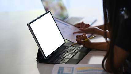 Cropped shot of businesswomen using digital tablet and discussing financial data at office desk.