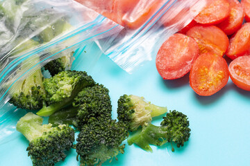 Plastic bag and sprinkled frozen vegetables on blue background