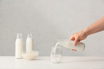 Woman pouring rice milk from bottle into glass on table