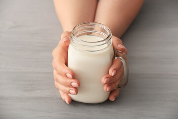 Female hands with mason jar of rice milk on table
