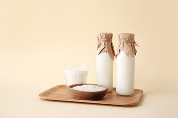 Bottles and glass of rice milk on color background