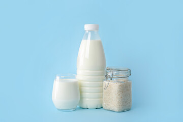 Bottle and glass of rice milk on color background