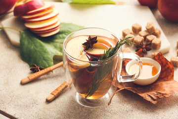 Tasty drink with spices and apple slices in cup on light background
