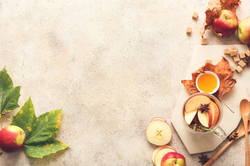 Tasty drink with spices and apple slices in cup on light background