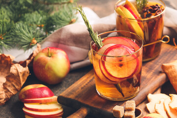 Tasty drink with spices and apple slices in glasses on wooden board