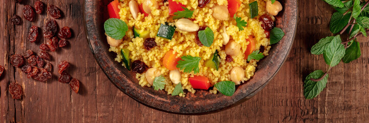 Moroccan couscous panorama with ingredients, top shot on a dark background