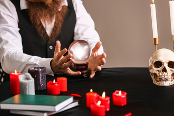 Male fortune teller with crystal ball at table