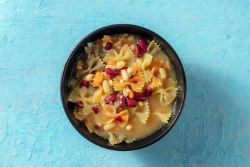 Vegan soup with pasta and beans, shot from the top on a blue background