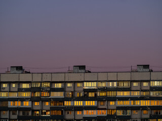 Rood and windows of the apartment house, which reflects sunset: gradients and many shades of yellow on a glass. Abstract urban landscape.