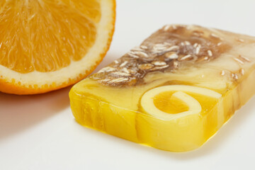 Cut orange and homemade soap on white background.