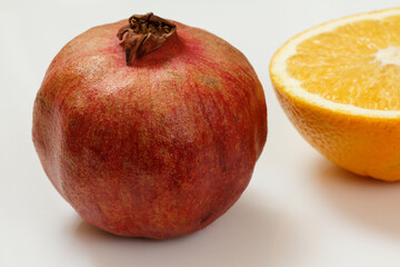 Pomegranate and cut orange on the white background.