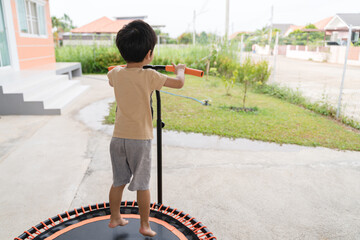 Asian boy playing or jumping on trampoline at the house yard