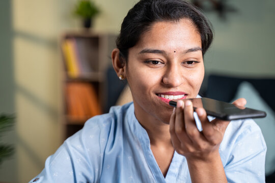 Close up shot of happy smiling young business woman talking on spaker of mobile phone at workplace during office hours.