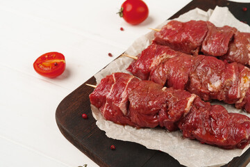 Raw marinated kebab on skewers on wooden background