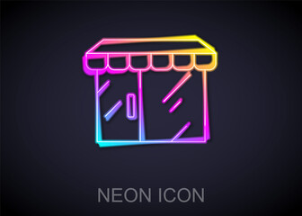 Glowing neon line Shopping building or market store icon isolated on black background. Shop construction. Vector.