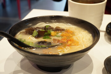 Hot ramen with transparent soup on black bowl