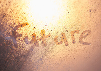 The word future on the window with water drops on sunny background. Fogged window calligraphy. Bright Future concept