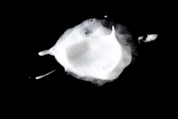 White soapy foam texture. Shampoo foam with bubbles.White facial foam creamy bubble soap sponge isolated on black background.