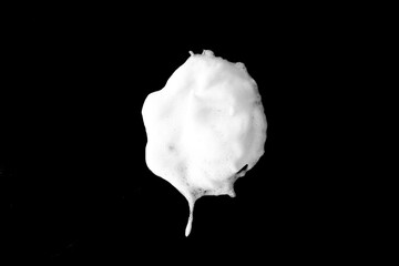 White soapy foam texture. Shampoo foam with bubbles.White facial foam creamy bubble soap sponge isolated on black background.