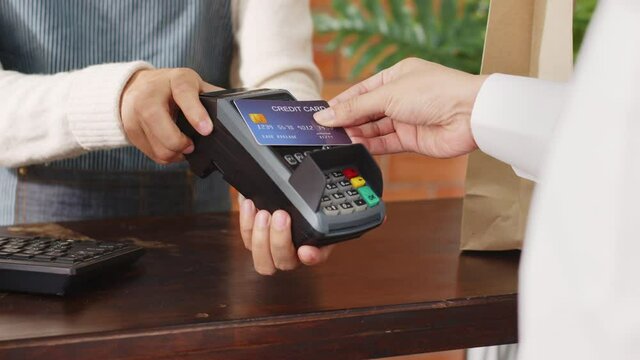 Customer using credit card for payment to owner at cafe restaurant, cashless technology and credit card payment concept