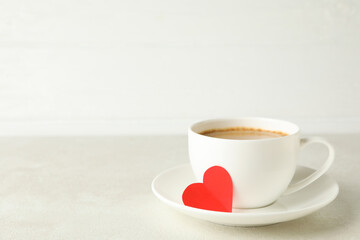 Cup of coffee with red heart on white textured table