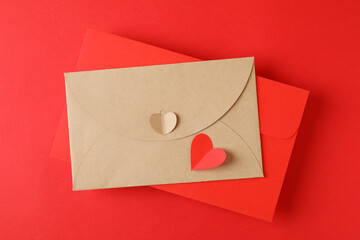 Envelopes and heart on red background, top view