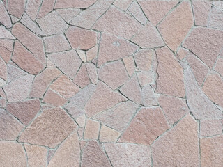 A wall with decorative cladding lined with granite pieces of tiles of different shapes and sizes