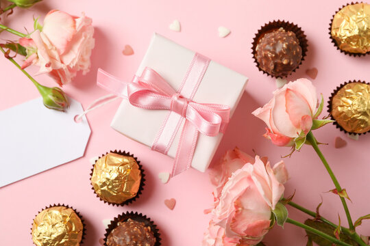 Concept of Valentine's day with roses, candies and gift box on pink background