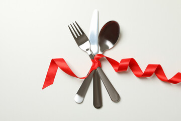 Cutlery with red ribbon on white background