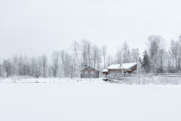 wooden cottages and footbridge on frozen lake shore
