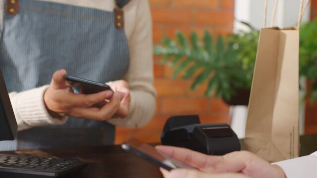 Customer using phone for payment at cafe restaurant, cashless technology and money transfer concept