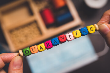 String a bracelet Wooden letter beads of Quarantine word, Close up woman hand string with a colourful Wooden letter beads, mood and tone concept.