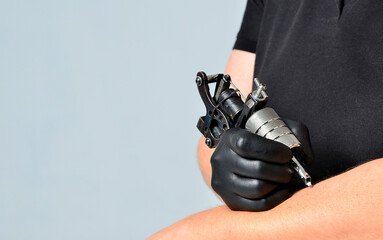 Hand in gloves holding tattoo machine