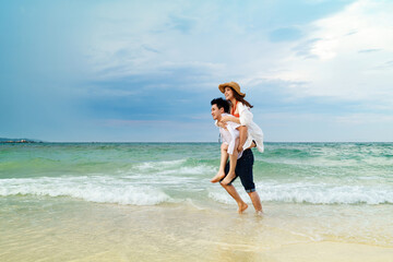couple piggyback ride on the sea beach at Koh MunNork Island, Rayong, Thailand, pronounced motion...
