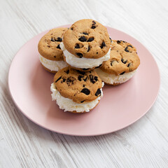 Homemade Chocolate Chip Cookie Ice Cream Sandwich on a pink plate on a white wooden table, side view. Close-up.