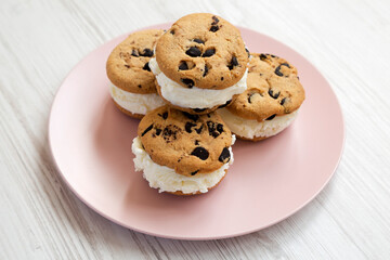 Homemade Chocolate Chip Cookie Ice Cream Sandwich on a pink plate on a white wooden table, side view.