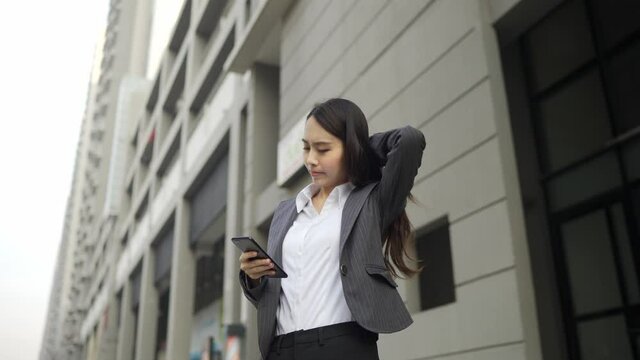 VDO Slow-motion. An attractive Asian businesswoman wearing a gray suit. Use a smartphone to connect to work in town.
