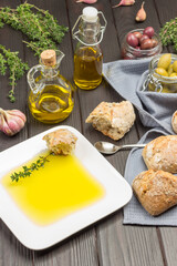Olive oil in a white plate with slice of bread and sprig of thyme