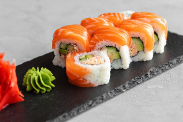 Sushi roll covered with fresh salmon served on plate