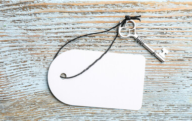 Key with blank tag on blue wooden background, top view. Keyword concept