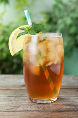 Delicious iced tea in glass on wooden table outdoors, closeup