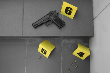 Crime scene with gun, bullet shells and evidence markers on stairs outdoors, flat lay. Detective...
