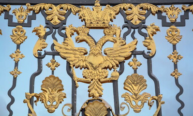 
The golden symbol of the Russian Empire -  double-headed eagle on old wrought-iron fence
