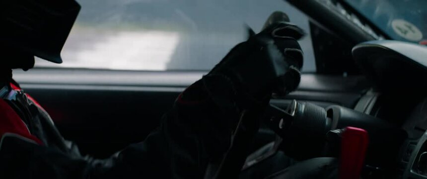 CU View of unrecognizable driver in protective wear driving a sports car, starting a race on a speedway. Shot with 2x anamorphic lens