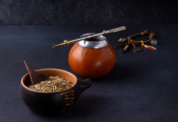 Mate, Paraguayan drink made from dried and crushed leaves of the Paraguayan holly. Calabash is a traditional vessel for preparing and drinking mate. On a black background.