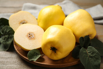 Naklejka na ściany i meble Fresh ripe organic quinces with leaves on wooden table, closeup