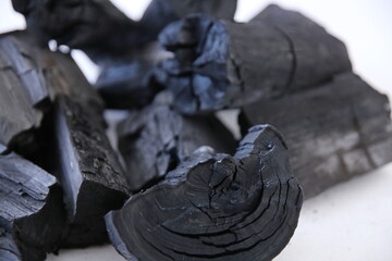 Black wood charcoal stacked on a white background.