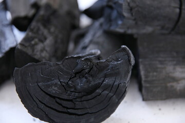 Black wood charcoal stacked on a white background.