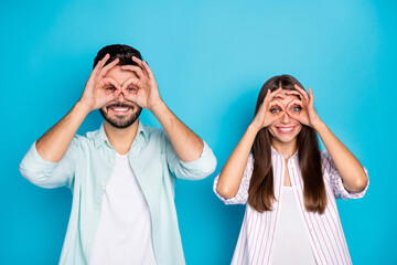 Photo of funny happy man and woman fooling make fingers ok sign glasses isolated on blue color background
